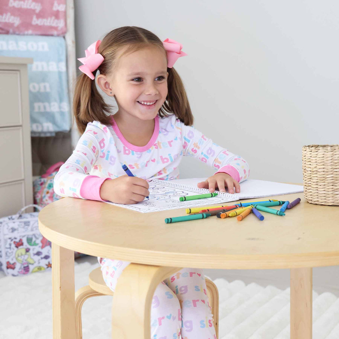 little girl sitting at table coloring a princess coloring book 