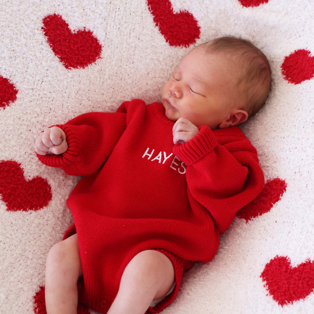 long sleeve embroidered red sweater bubble romper laying on a heart cuddlelane blanket 