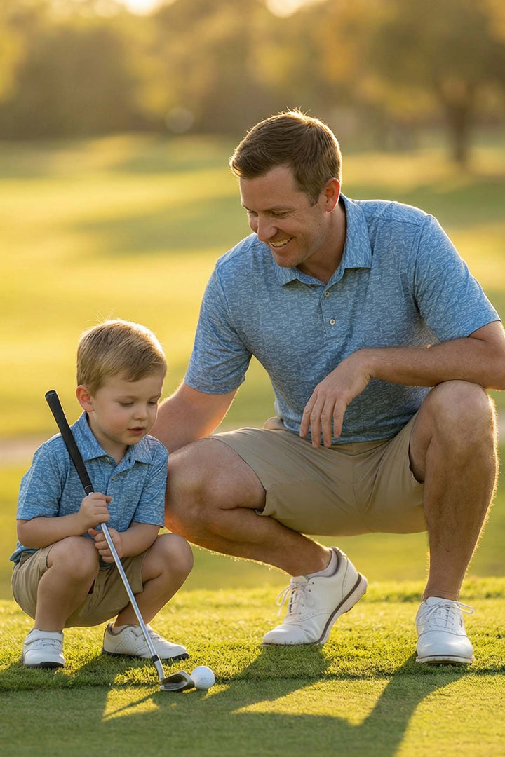 father and son bending down on golf course in fishing polo shirts 