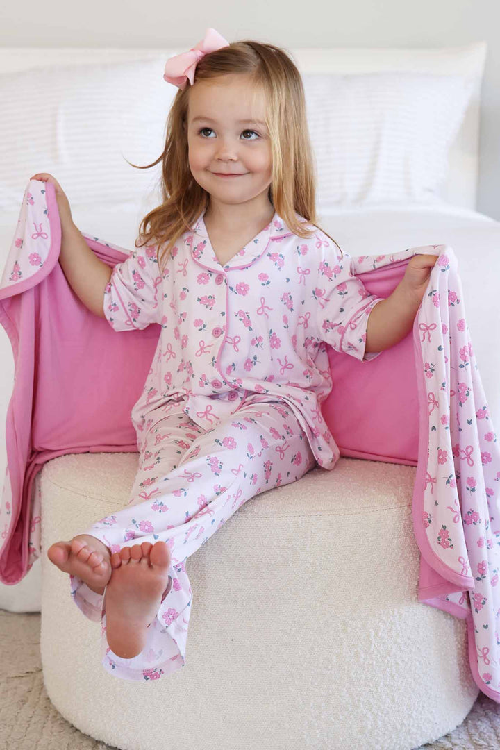 girl sitting on ottoman in ribbon and roses flare lounge set with blanket wrapped around her shoulders 