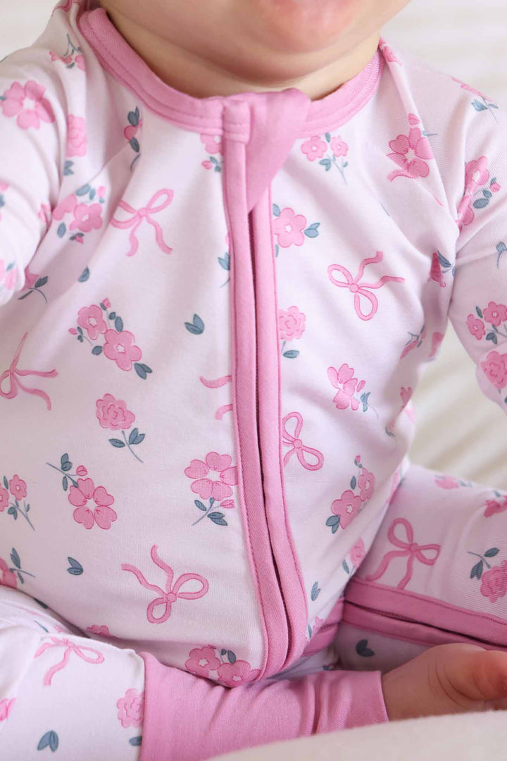 closeup of ribbon and roses pink convertible zip romper for girls with pink trim 