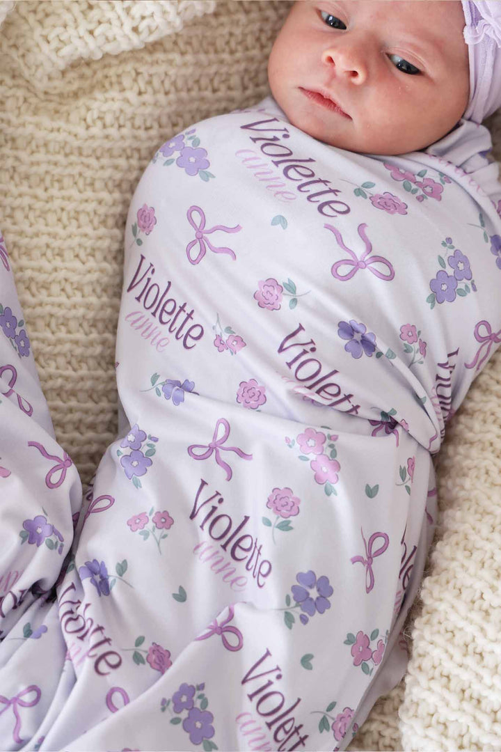 closeup of purple ribbon and roses personalized swaddle blanket for newborn girls 