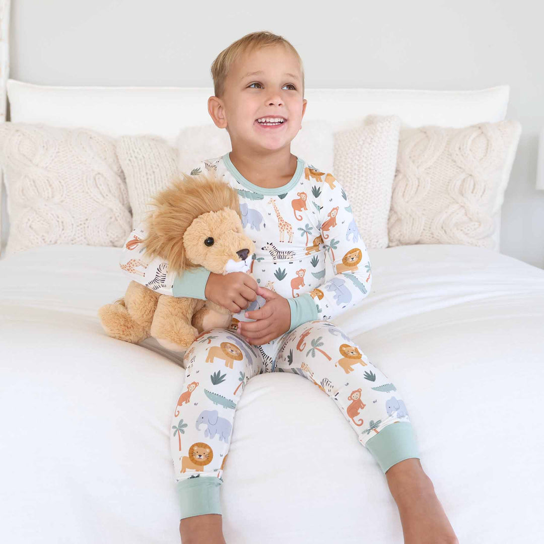boy wearing safari animal two piece pajama set holding a lion stuffed animal 