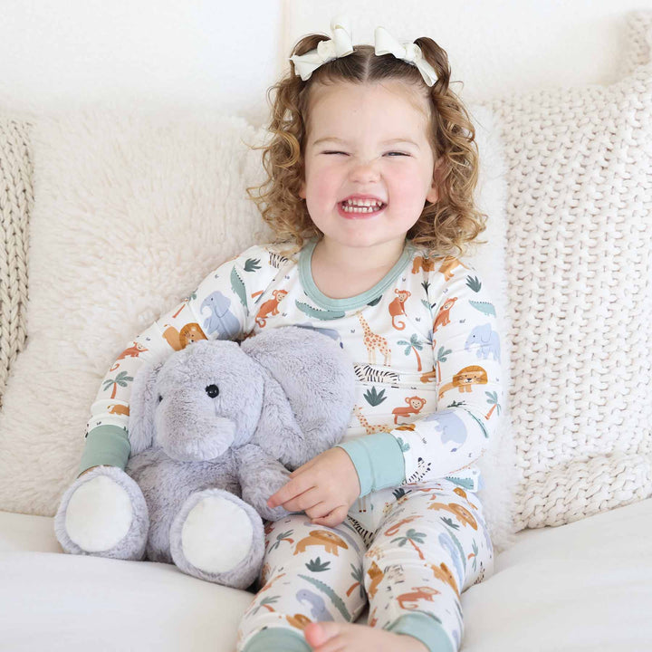 girl wearing safari themed two piece pajama set with elephant stuffed animal
