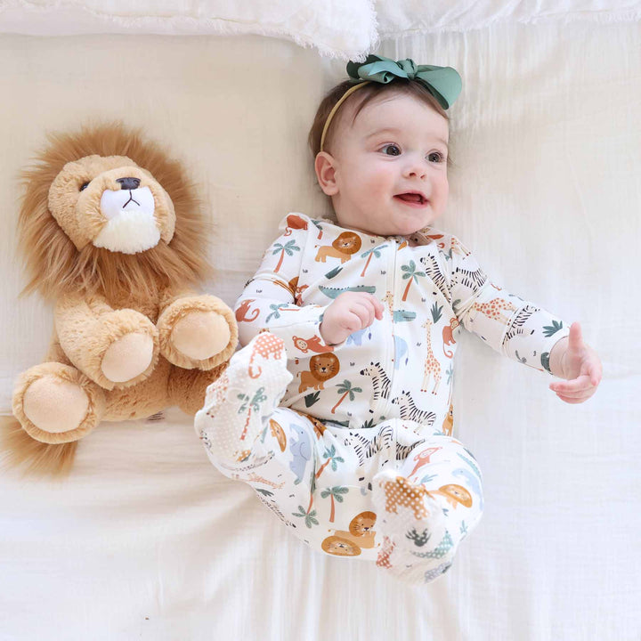baby girl wearing safari animal footie pajama with matching green bow and lion stuffed animal
