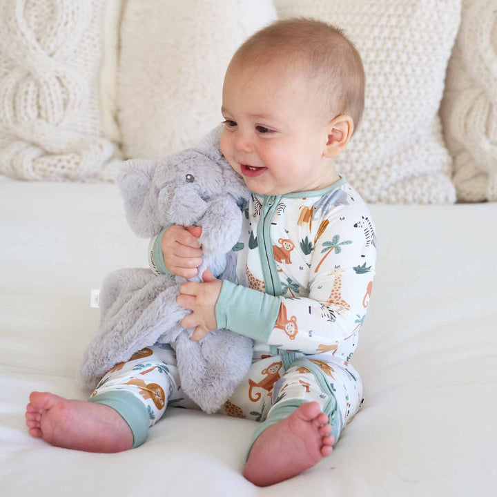 boy wearing a safari themed convertible zip romper pajama holding an elephant lovey