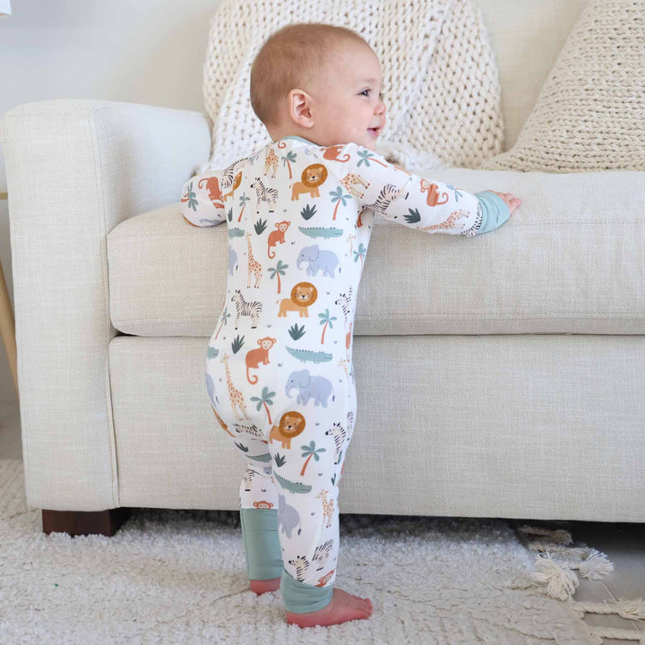 standing toddler wearing lion, elephant, giraffe, crocodile and palm tree zip romper pajama 