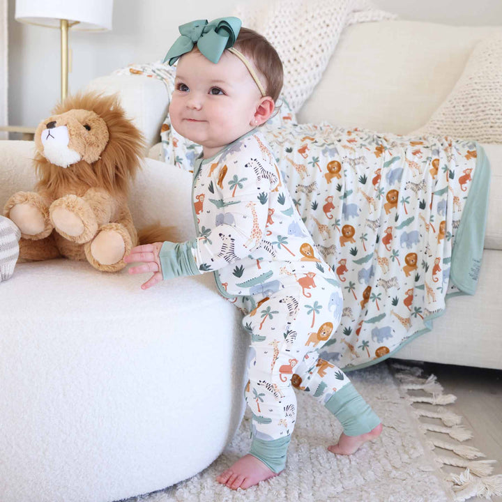 standing toddler girl wearing safari animal pajama romper with lion stuffed animal