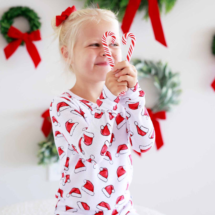 sibling matching christmas pajamas with santa hats 