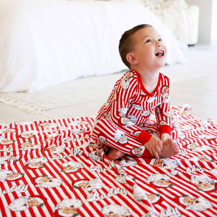 Santa Claus Lane Personalized Kids Blanket with little boy wearing matching Two Piece Pajama Set