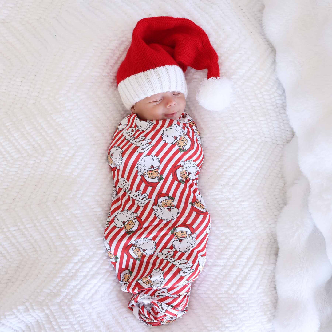 Baby wrapped in the Santa Claus Lane Personalized Swaddle Blanket with mini santa hat