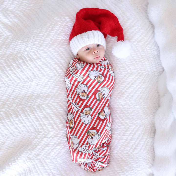 Baby wrapped in the Santa Claus Lane Personalized Swaddle Blanket with mini santa hat