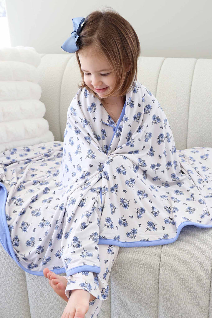girl sitting on couch with blue rose bamboo blanket wrapped around her 