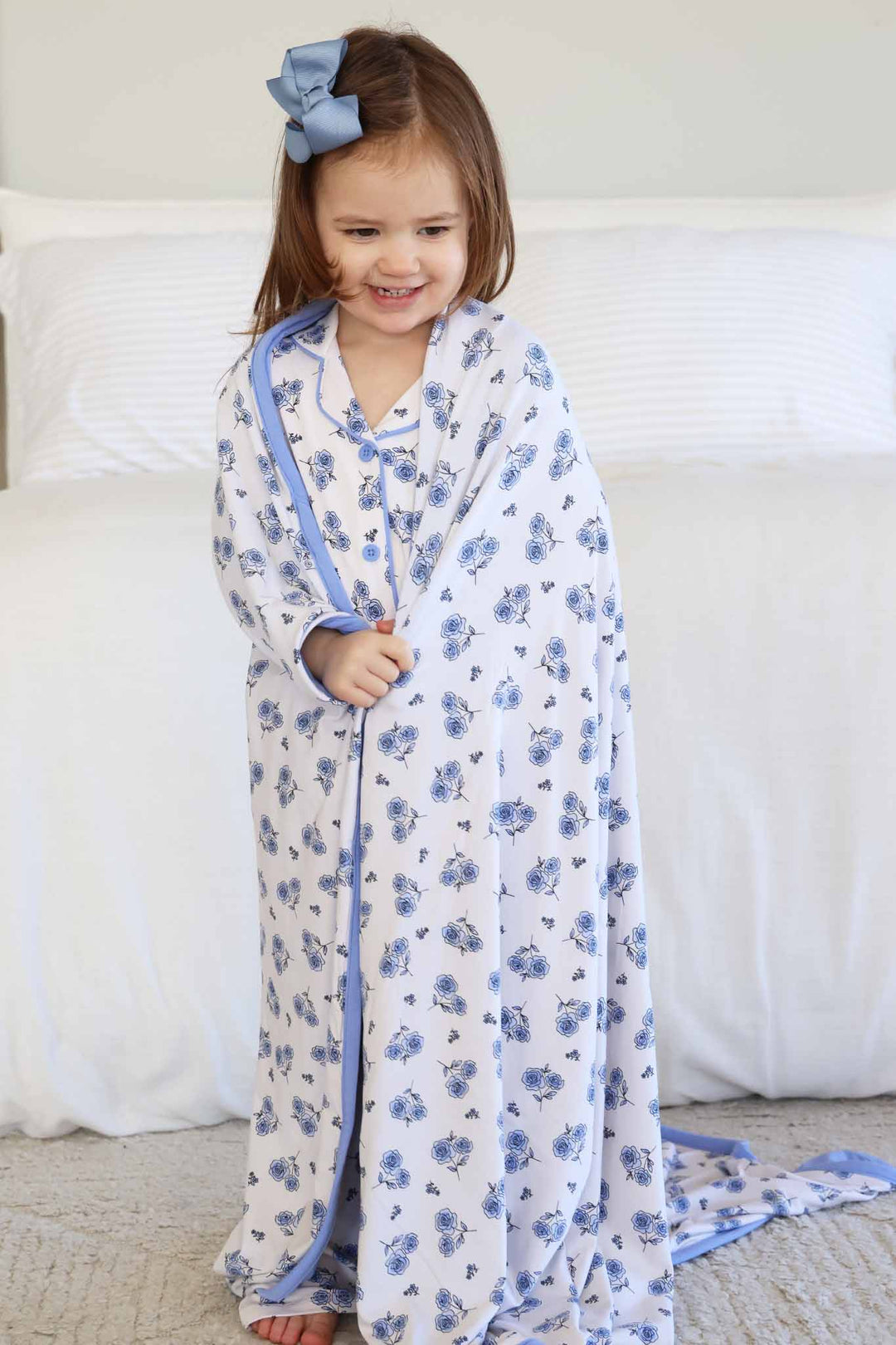 standing girl with a white bamboo blanket with blue roses wrapped around her 