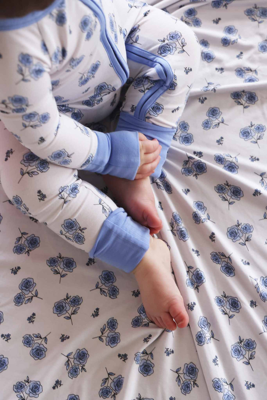 baby girl in sapphire garden convertible zip romper sitting on a matching bamboo blanket 