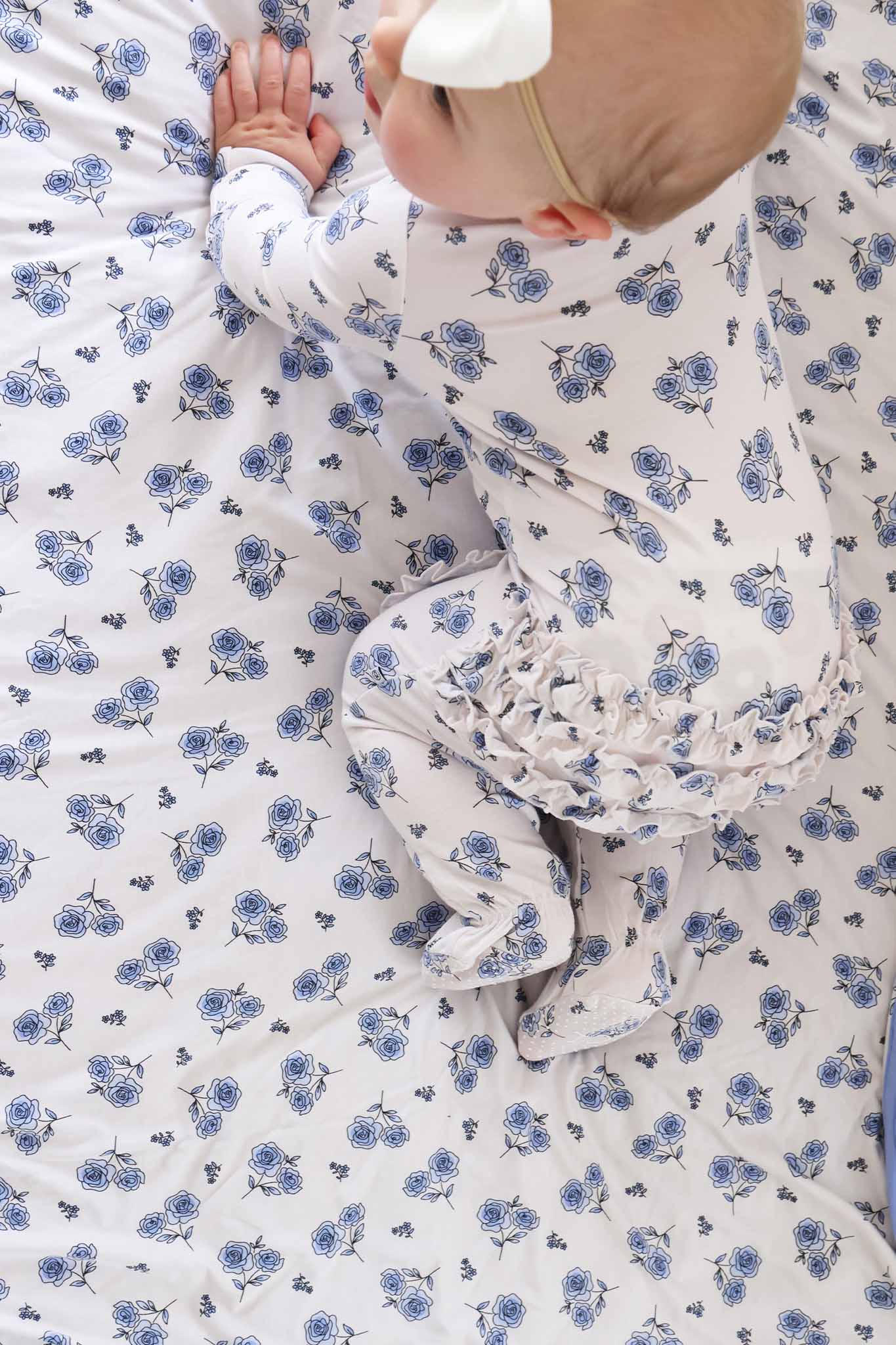 baby girl in sapphire garden bamboo ruffle zipper footie pajama crawling on a matching bamboo blanket 