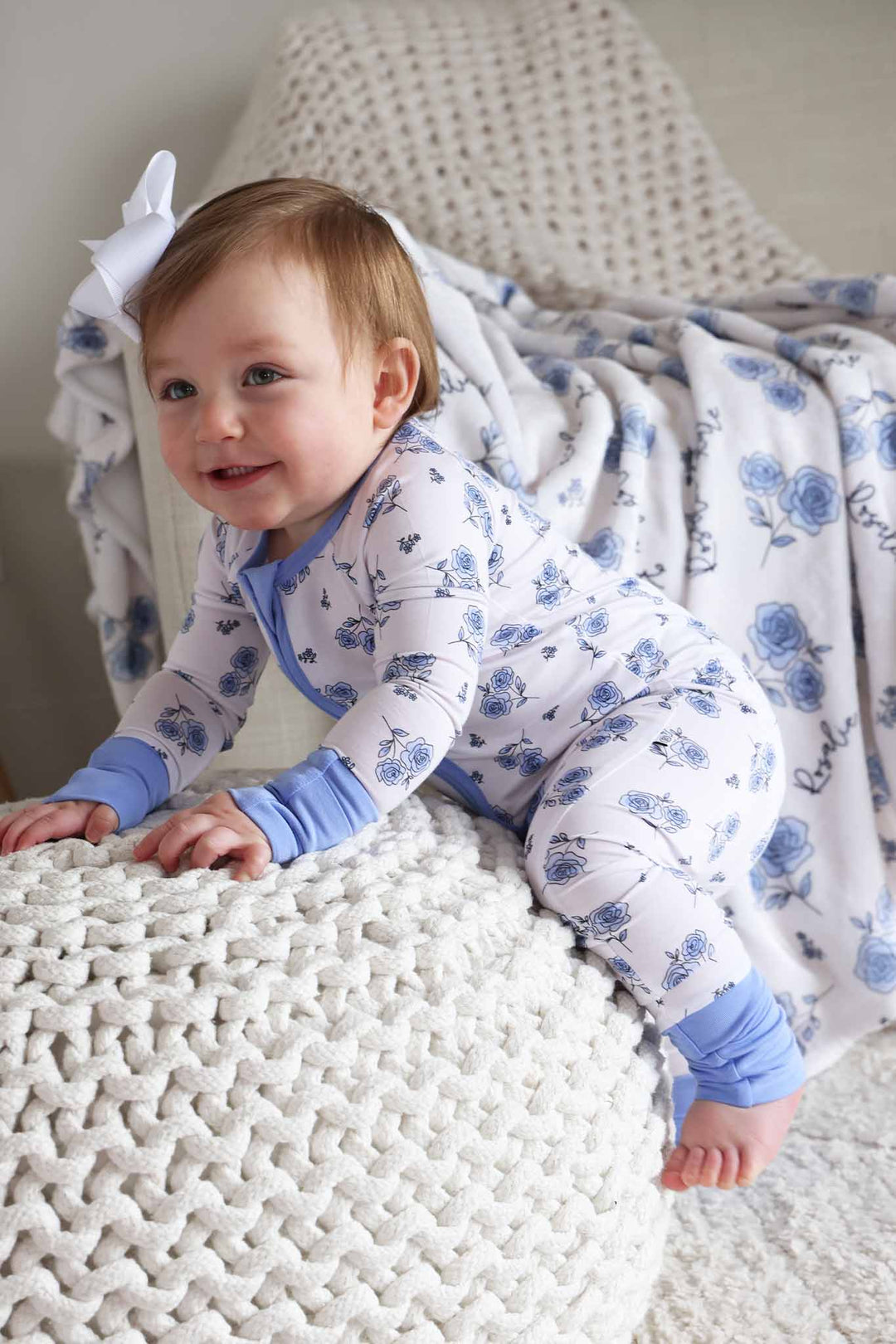 baby girl climbing on top of ottoman in sapphire garden convertible zip romper 