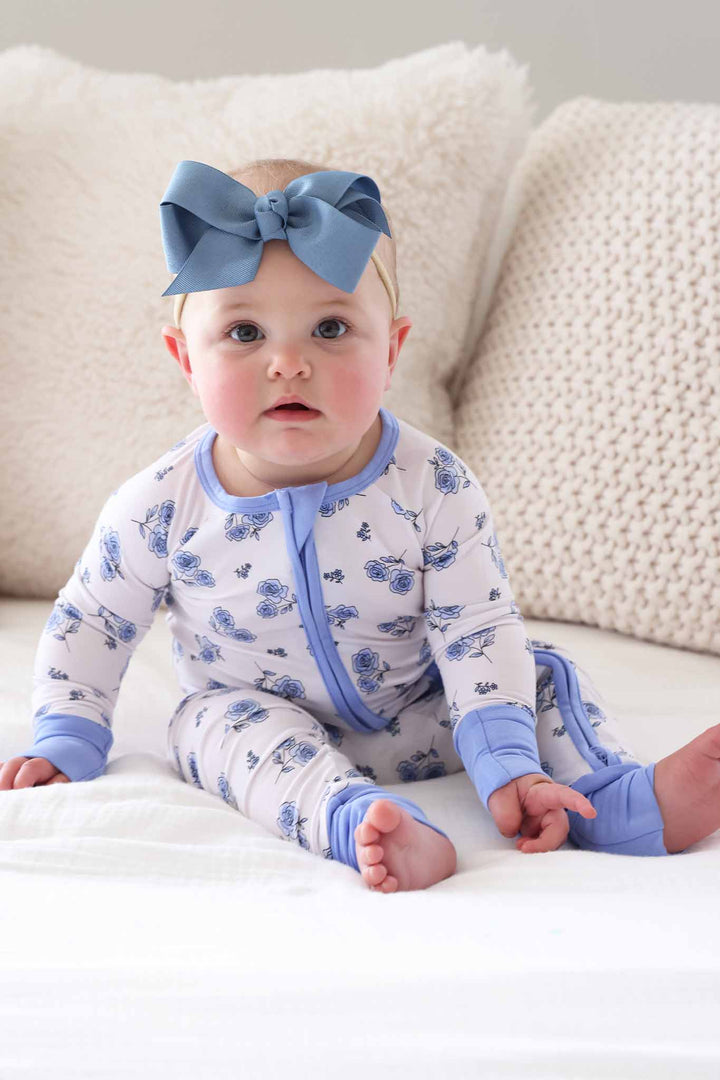 sitting baby girl in blue rose convertible zip romper with  matching blue ribbon bow headband 