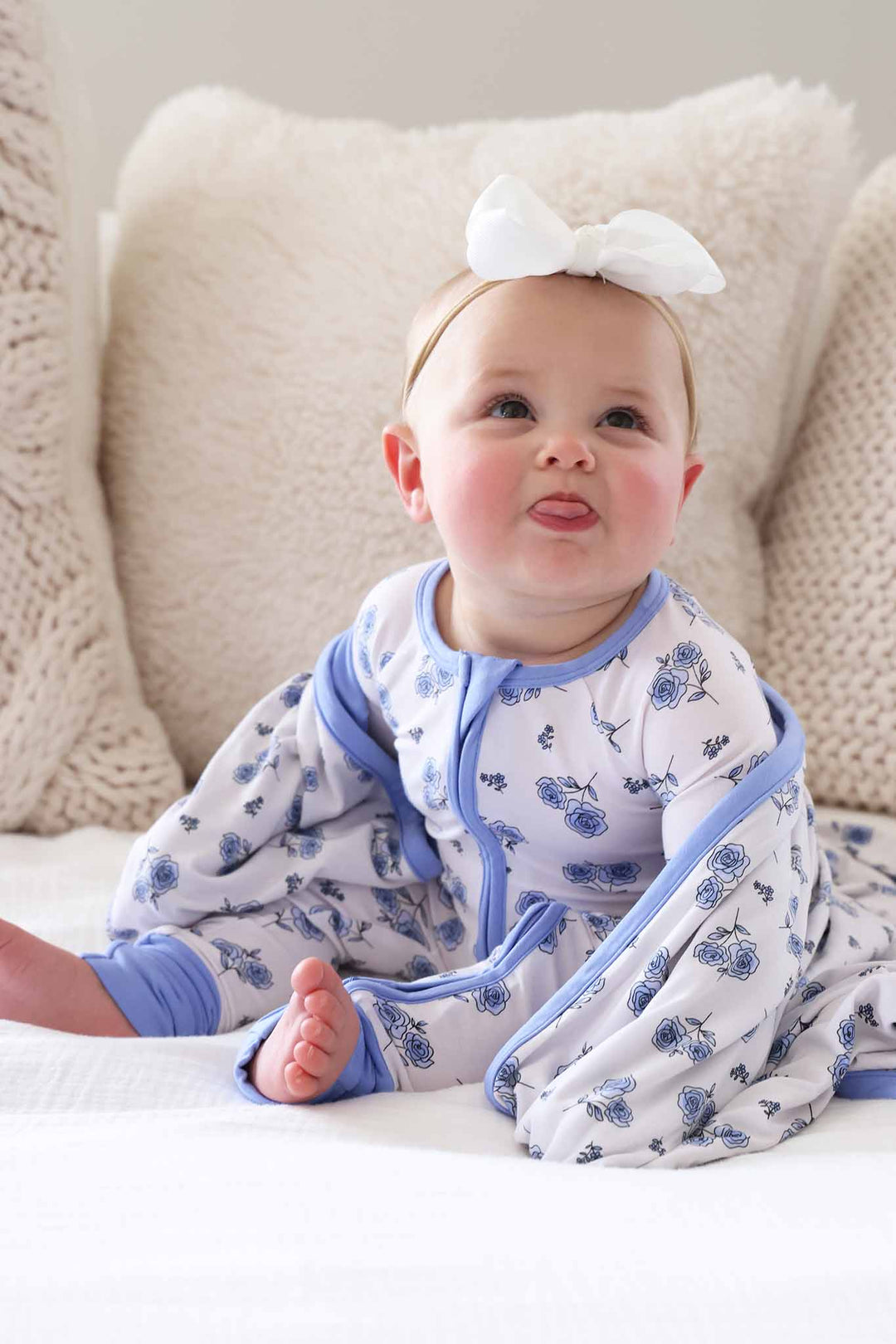 girl sitting on bed in sapphire garden convertible zip romper pajama with matching bamboo blanket wrapped around her 