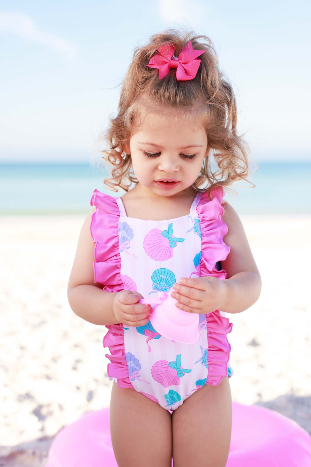 girl at beach in seashell ruffled one piece swimsuit