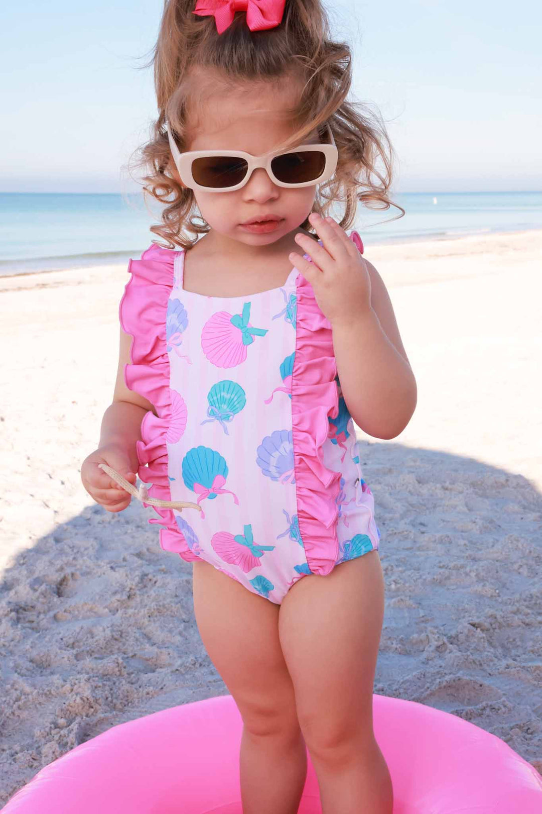 girl standing in inner tube on the beach in seaside sweetie double ruffle one piece swimsuit