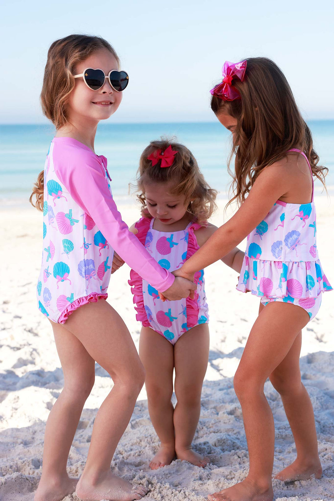 girls standing in a circle on the beach in seaside sweetie swimsuits 