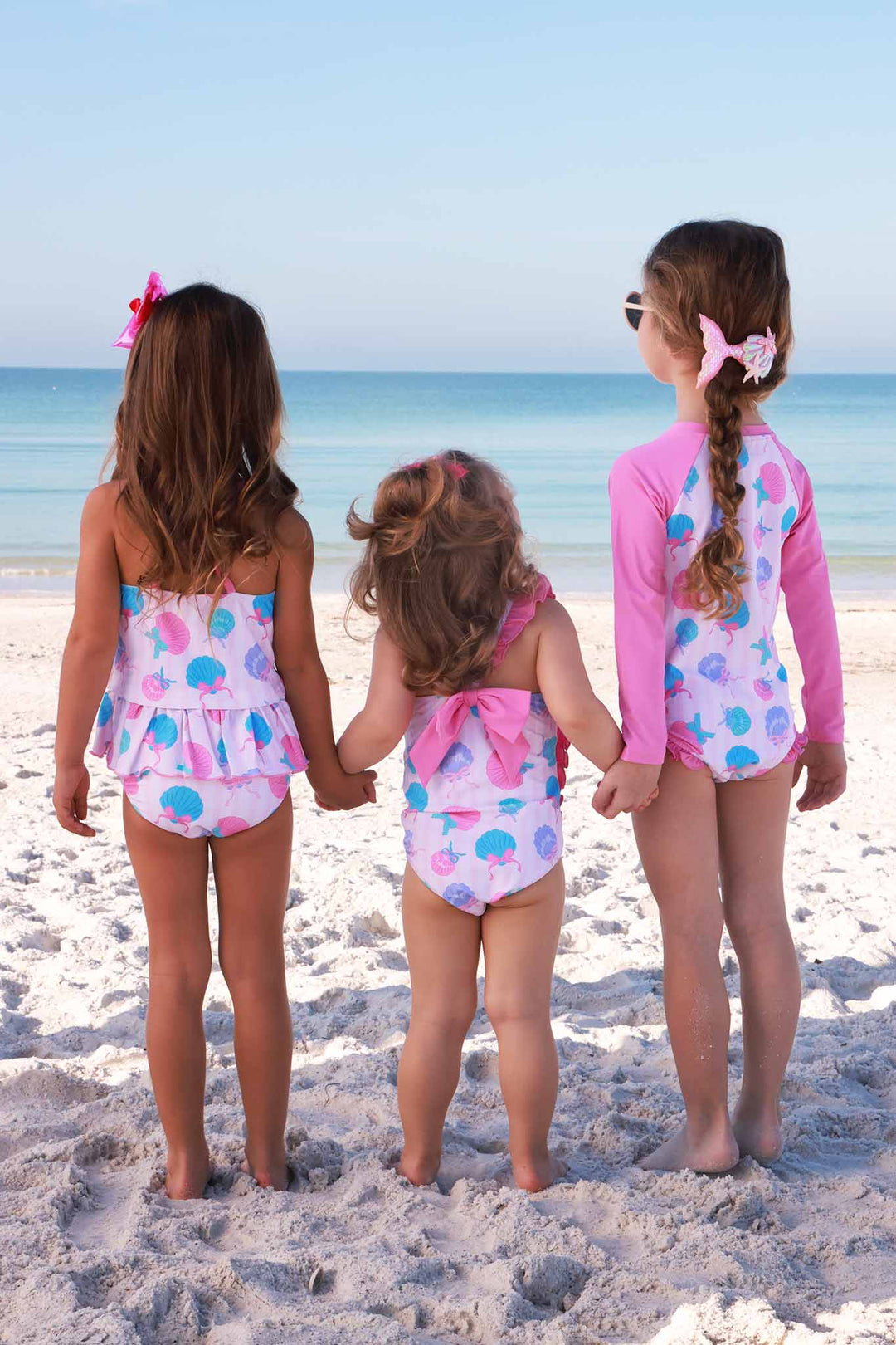 girls standing on the beach in with matching seaside sweetie girl swimsuits 