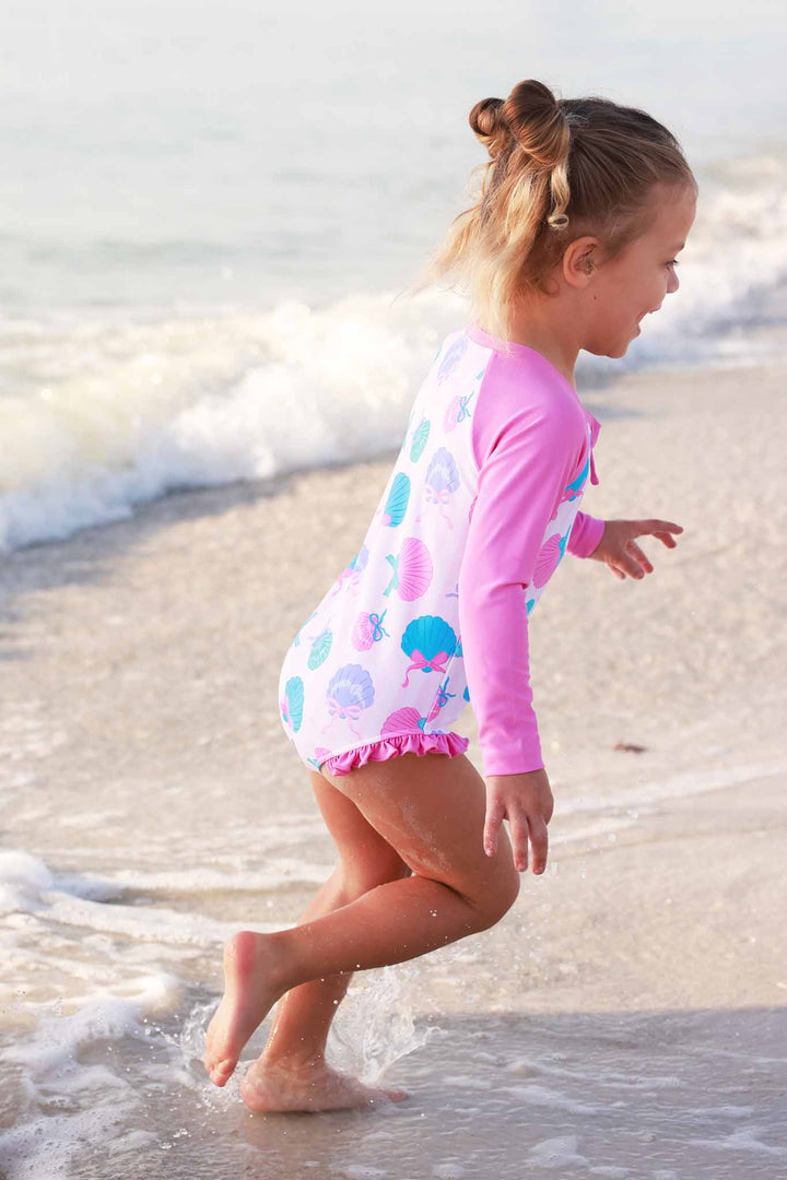 girl running on the beach in seashell long sleeve rash guard swimsuit 