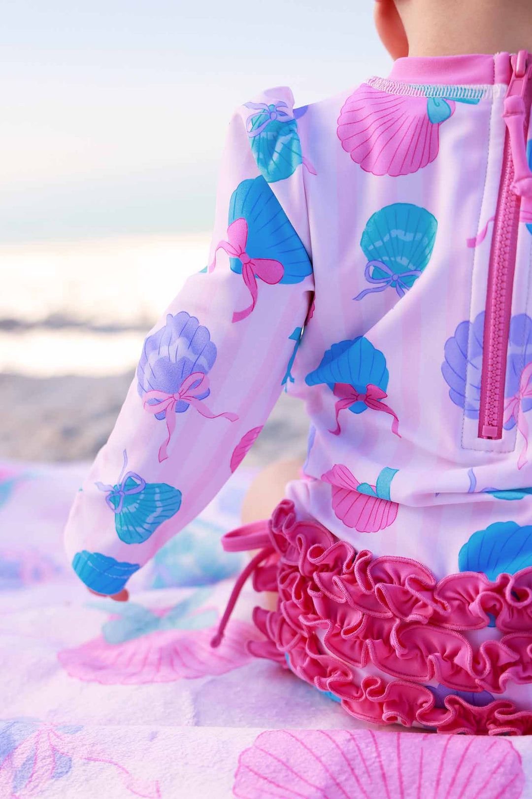 closeup of seashell ruffle bottom rash guard swimsuit for girls 