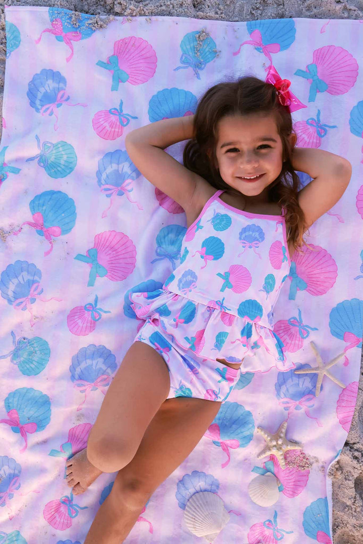 girl laying on personalized seashell beach towel wearing a matching tankini