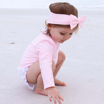 pink and white seersucker rash guard for babies with ruffle bottom 