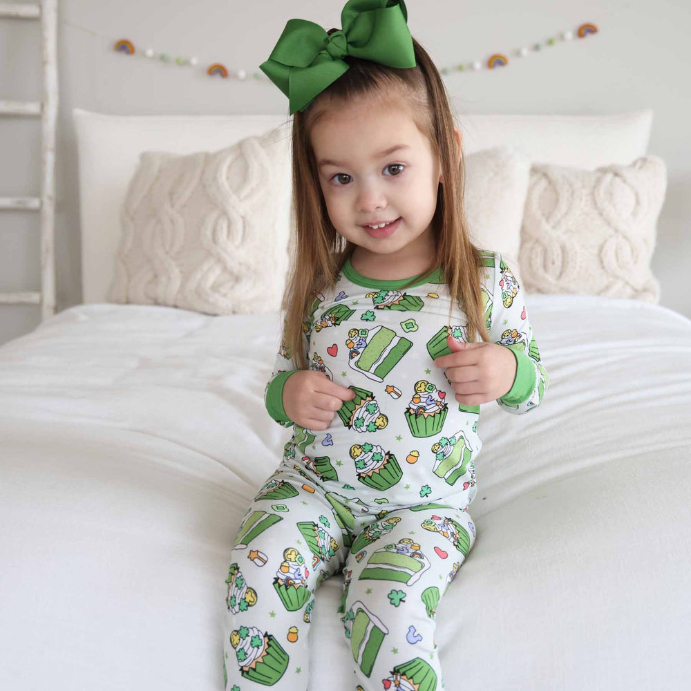 girl wearing two piece st. patrick's day pajama set with cake and cupcakes on it