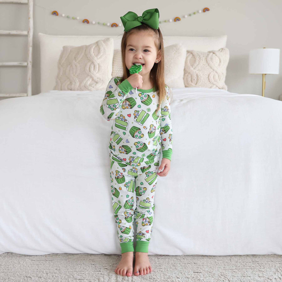 girl wearing shamrock sweets two piece pajama set biting a clover lollipop