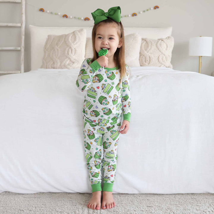 girl wearing shamrock sweets two piece pajama set biting a clover lollipop