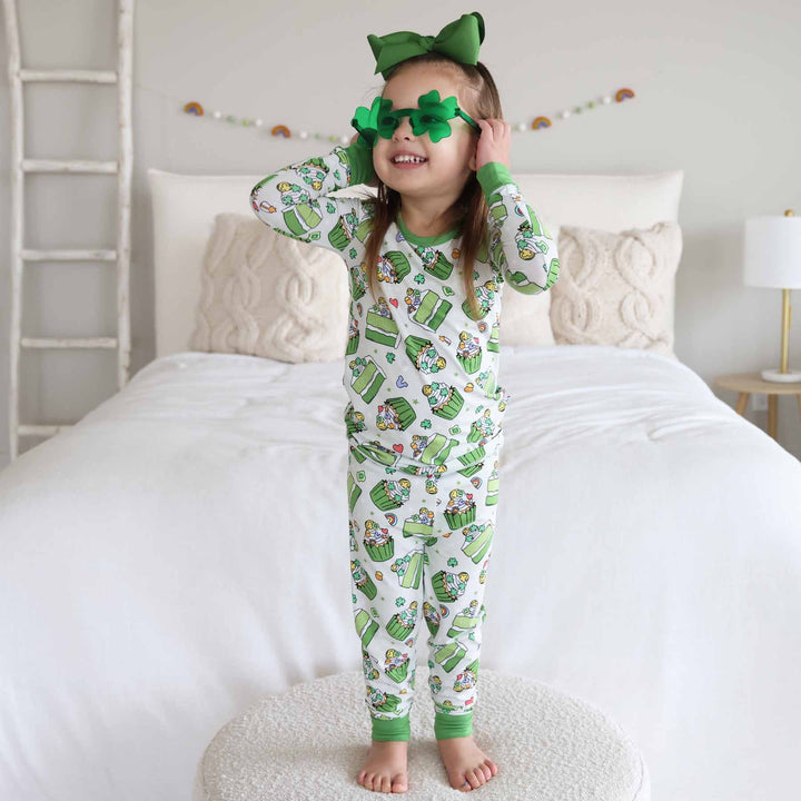 girl wearing shamrock sweets two piece pajama set with clover sunglasses and green bow