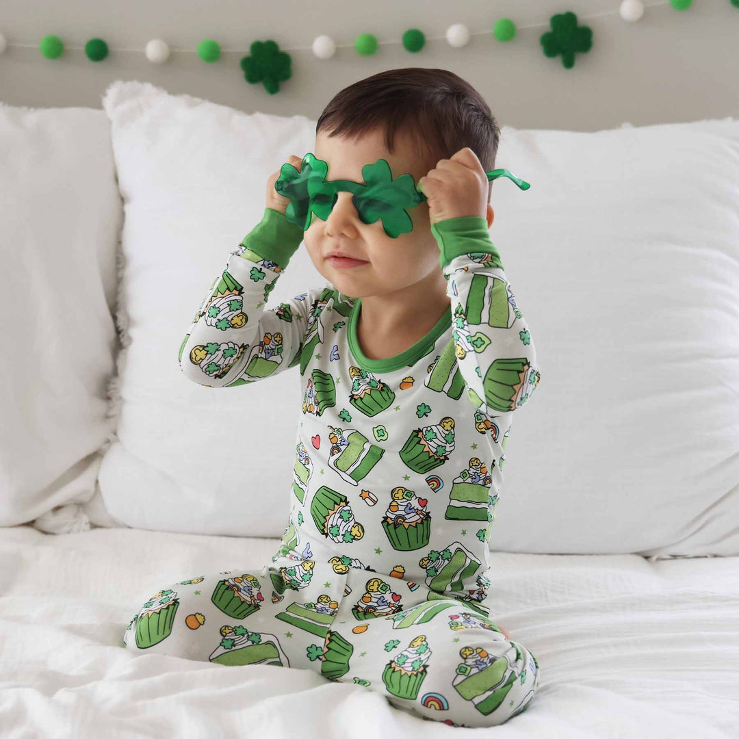 boy wearing a green dessert st. patrick's day pajama set with green clover glasses