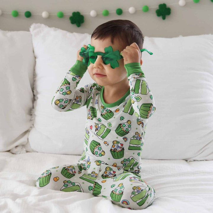 boy wearing a green dessert st. patrick's day pajama set with green clover glasses