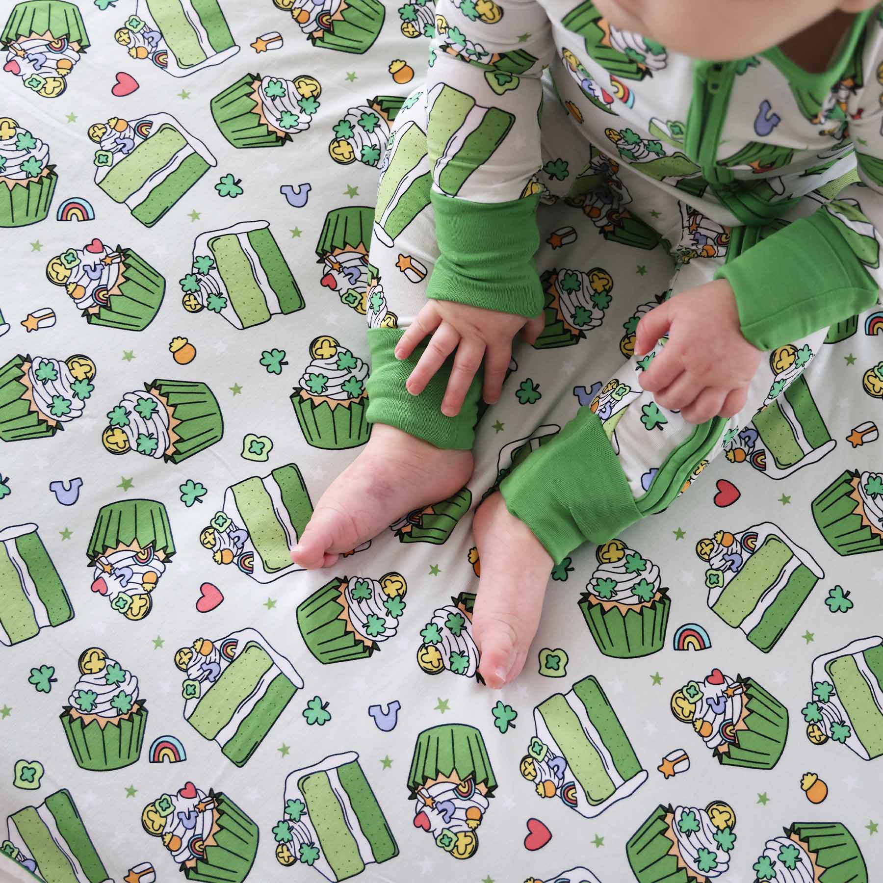 Baby wearing the Shamrock Sweets zip romper and sitting on the Double Sided Bamboo Blanket