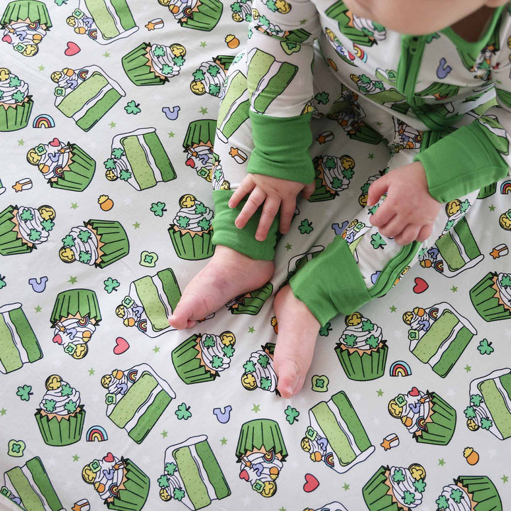 Baby wearing the Shamrock Sweets zip romper and sitting on the Double Sided Bamboo Blanket