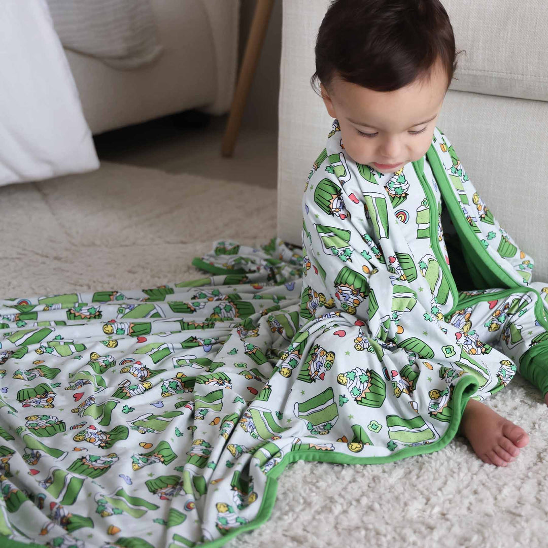 Baby wearing the Shamrock Sweets zip romper and matching Double Sided Bamboo Blanket