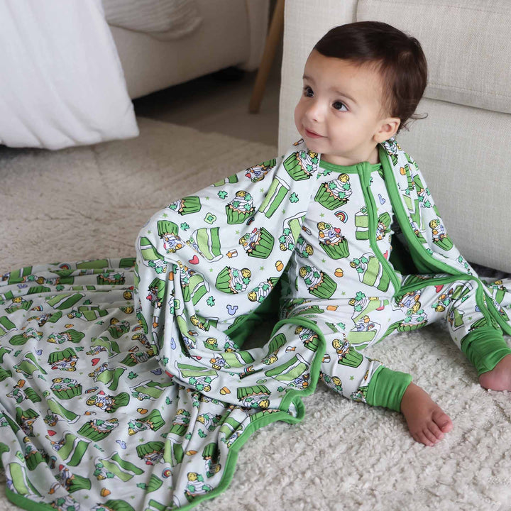 Baby wearing the Shamrock Sweets zip romper and matching Double Sided Bamboo Blanket