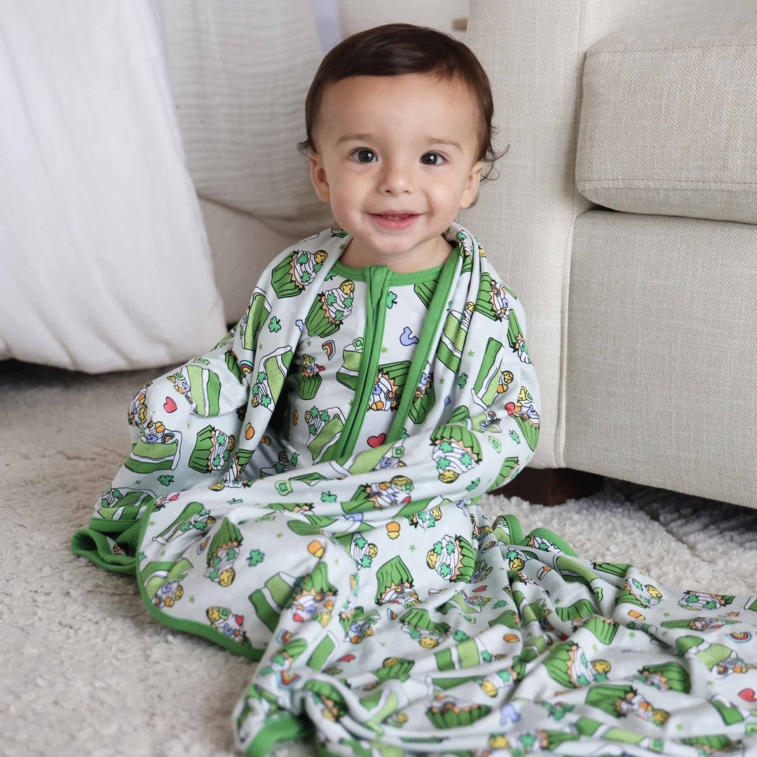 Baby wearing the Shamrock Sweets zip romper and matching Double Sided Bamboo Blanket