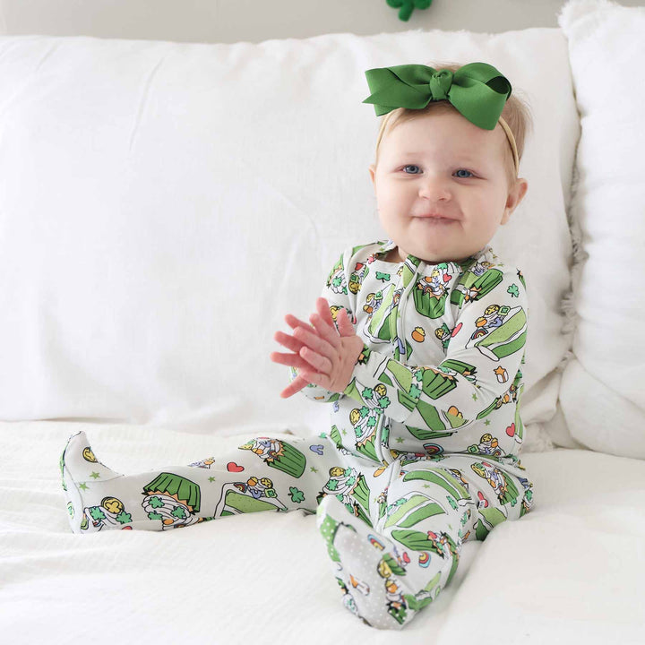 baby girl wearing a cake and cupcake bamboo footie with lucky charms on top and clovers