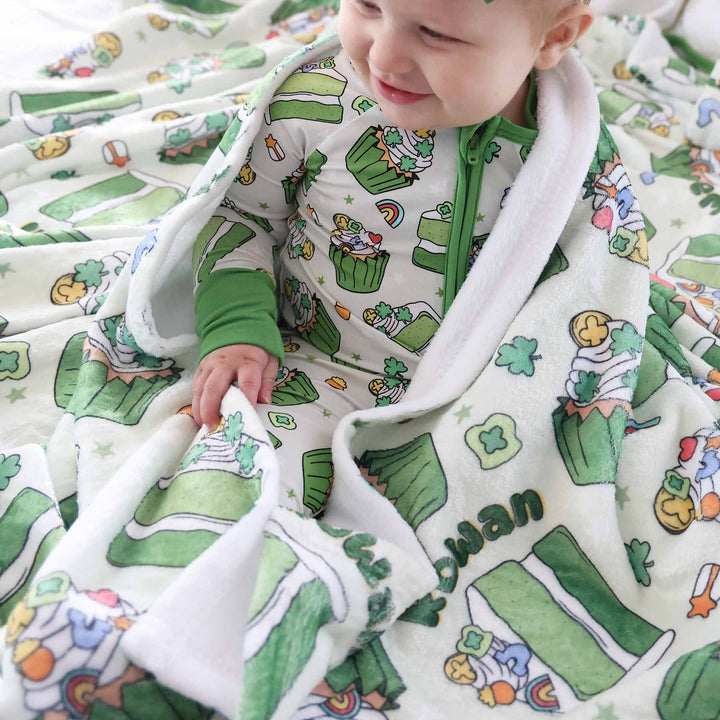 baby girl wearing a shamrock sweets convertible zip romper with a matching personalized blanket draped over her shoulders 