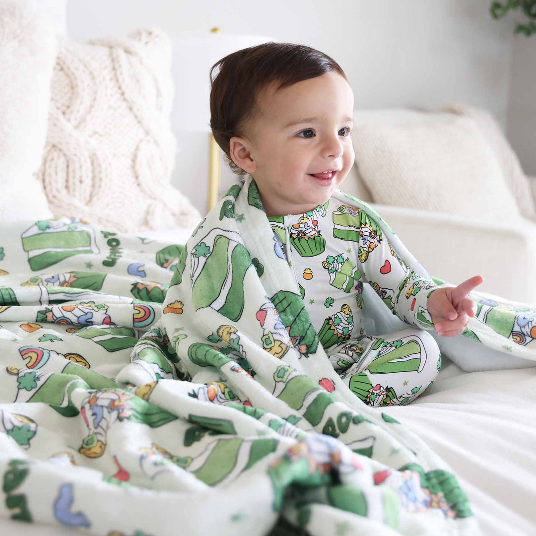 little boy in a green dessert st. patrick's day footie with a matching personalized blanket draped over his shoulders 