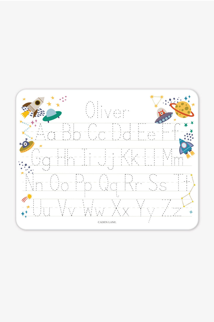 Flat lay of a personalized Caden Lane Star Explorer alphabet whiteboard, showing rockets, UFOs, and planets with tracing letters and custom name