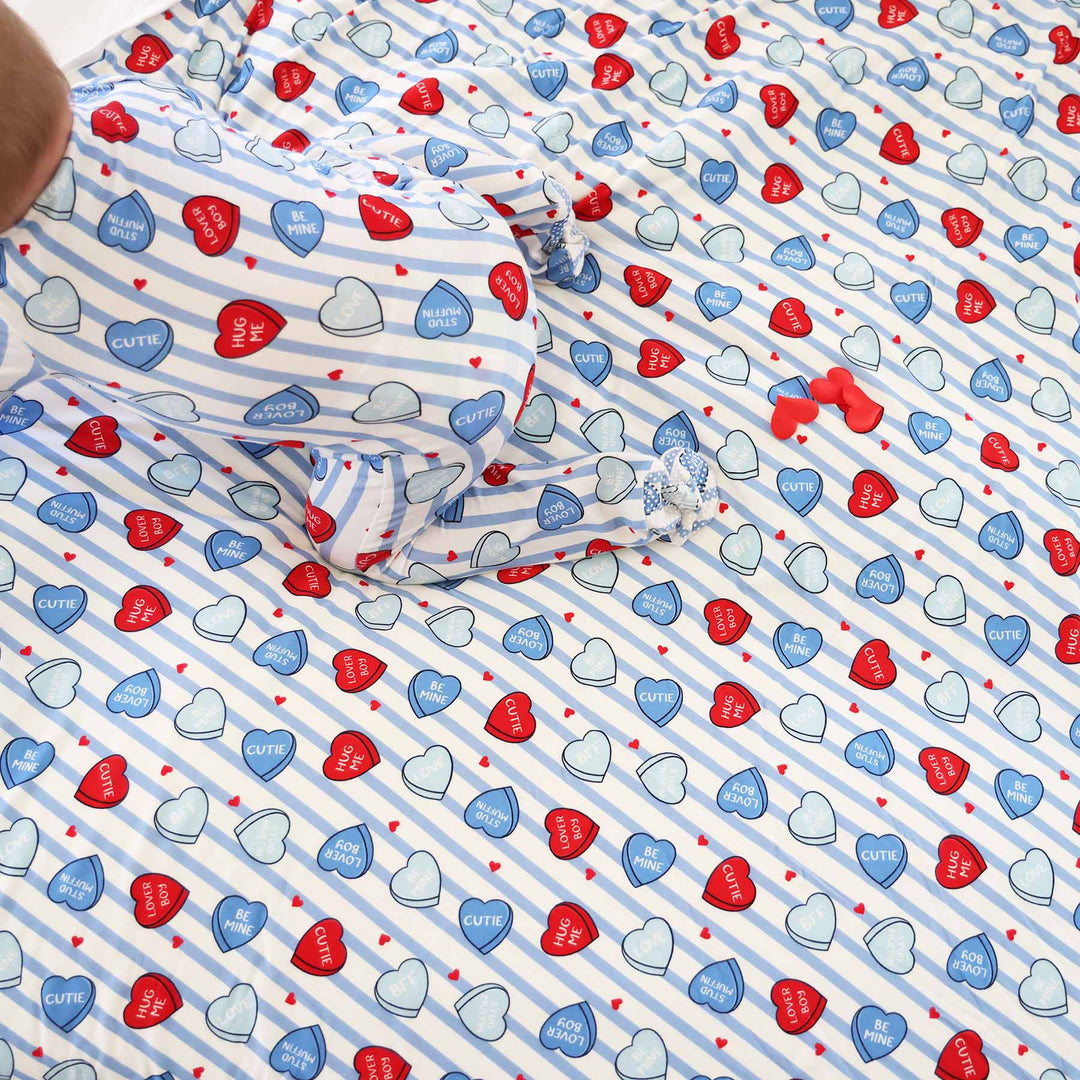 baby wearing the blue sweet like candy zipper footie crawling on a matching bamboo blanket 