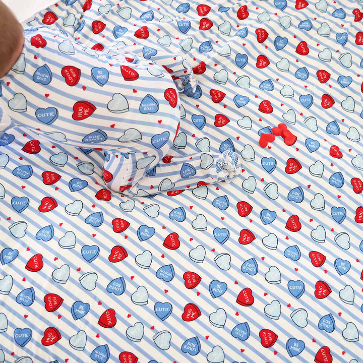 baby wearing the blue sweet like candy zipper footie crawling on a matching bamboo blanket 