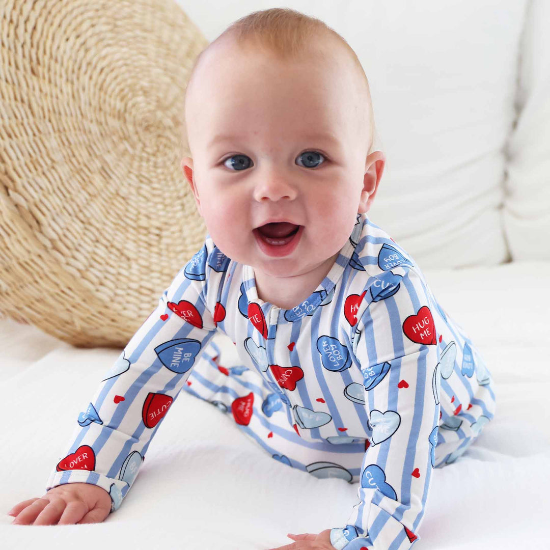 crawling baby boy wearing a blue striped conversation heart bamboo baby footie pajama 