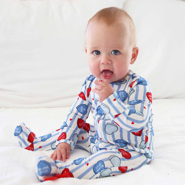 sitting baby wearing a blue striped zipper footie with heart candy that says stud muffin, hug me, be mine, cutie and more 